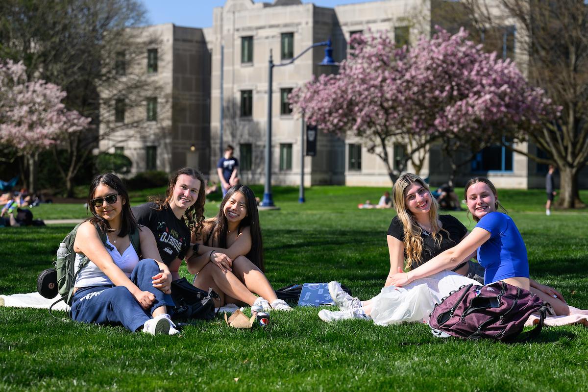 一群学生坐在户外的草地上，面带微笑.